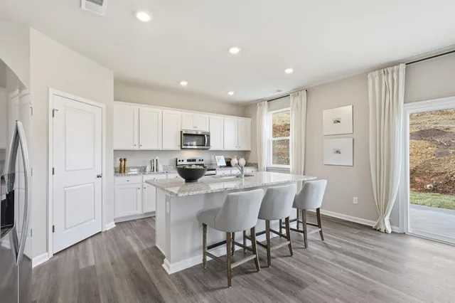 a kitchen with stainless steel appliances a dining table chairs refrigerator and cabinets