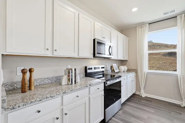 a kitchen with stainless steel appliances granite countertop white cabinets a window and a sink