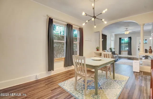 a dining room with wooden floor a chandelier a wooden table and chairs