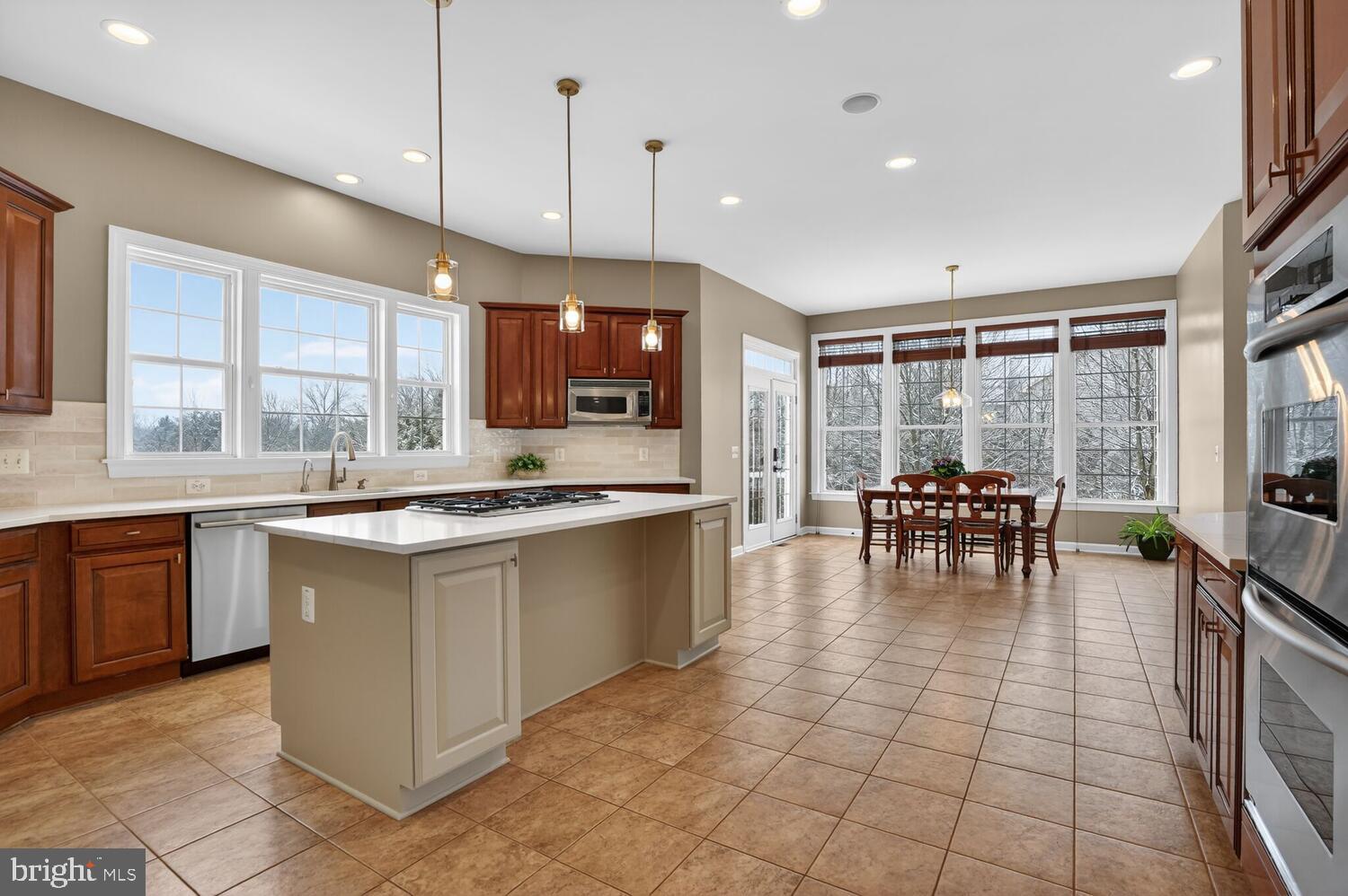 43024 La Riva Drive Ashburn, VA 20148 - Photo 14 of 63 a kitchen with stainless steel appliances granite countertop a stove a sink a dining table and chairs