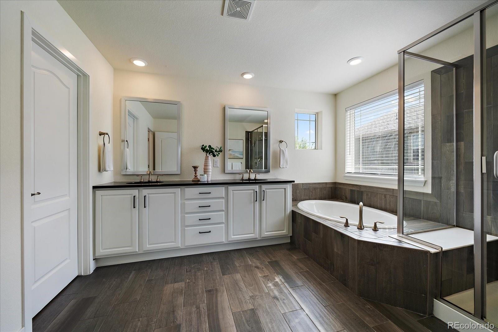 16062 Red Bud Loop Parker, CO 80134 - Photo 24 of 36 a spacious bathroom with a granite countertop tub sink and mirror