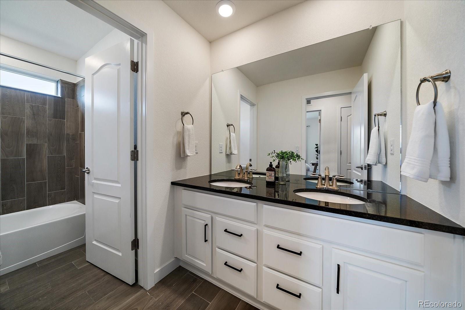 16062 Red Bud Loop Parker, CO 80134 - Photo 29 of 36 a bath room with double vanity sink and a mirror