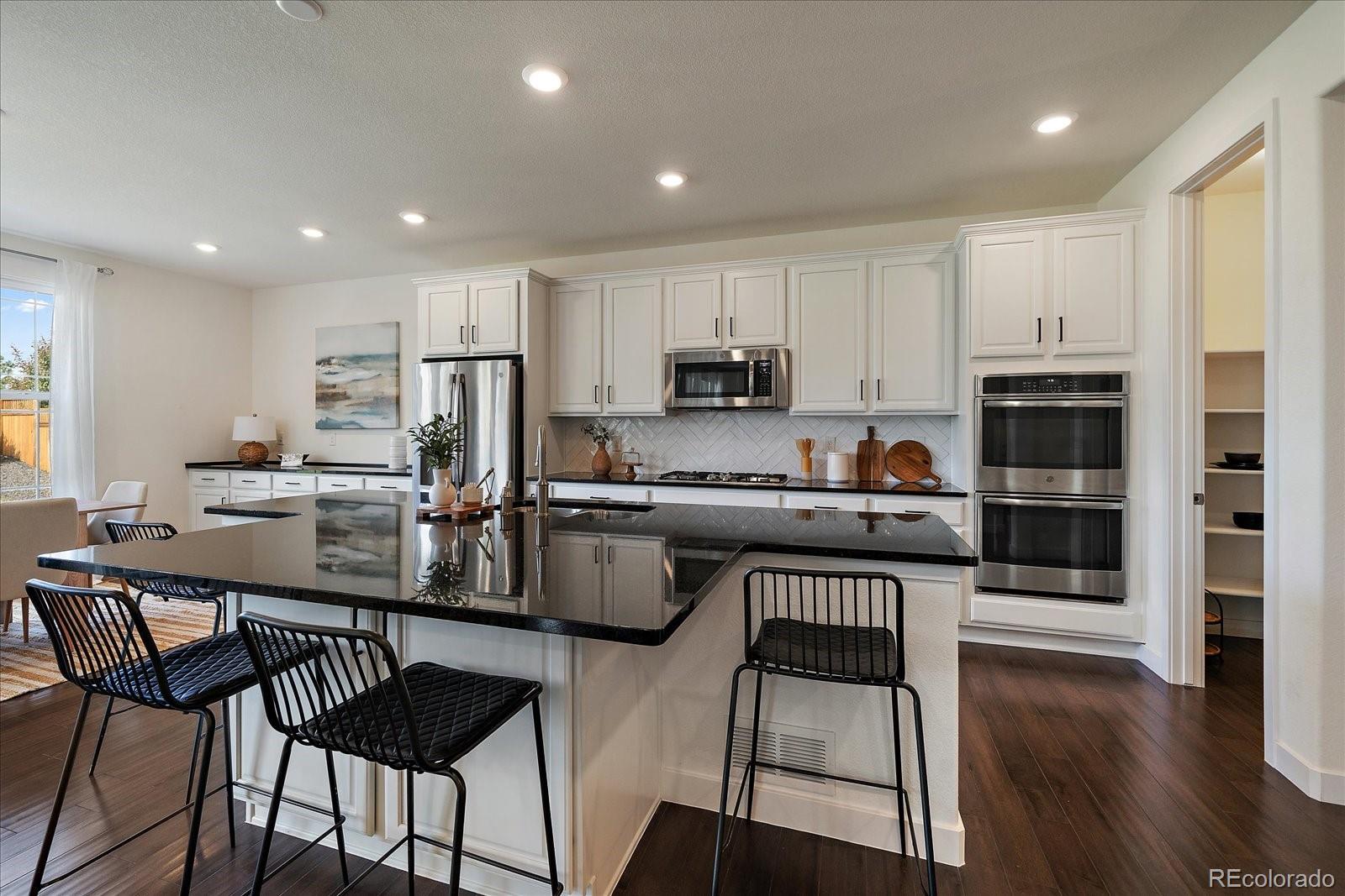 16062 Red Bud Loop Parker, CO 80134 - Photo 8 of 36 a kitchen with stainless steel appliances a stove a sink a microwave a refrigerator and cabinets