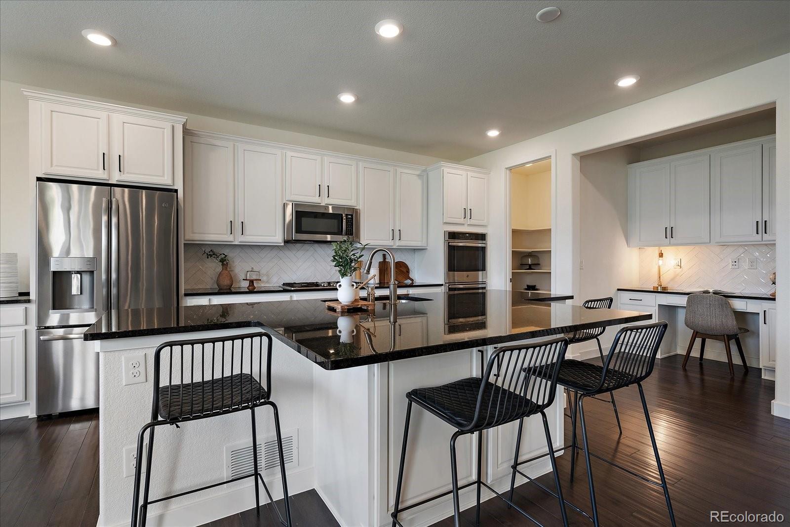 16062 Red Bud Loop Parker, CO 80134 - Photo 9 of 36 a kitchen with stainless steel appliances granite countertop a stove a refrigerator a sink a stove and white cabinets with wooden floor