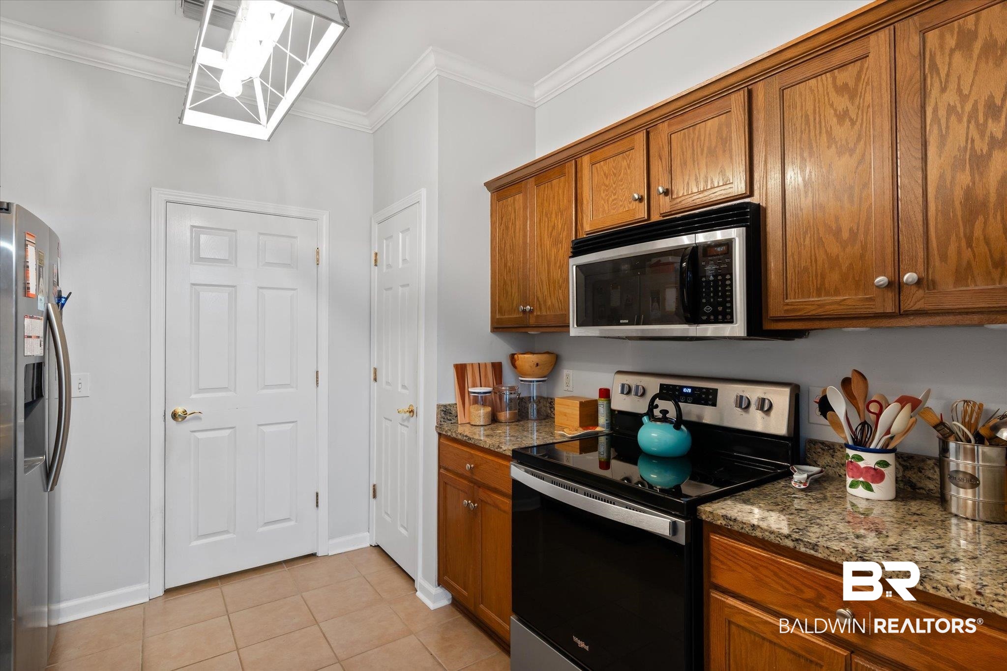 3876 Emerille Drive Foley, AL 36535 - Photo 11 of 31 Kitchen featuring stone countertops, light tile patterned floors, crown molding, and stainless steel appliances
