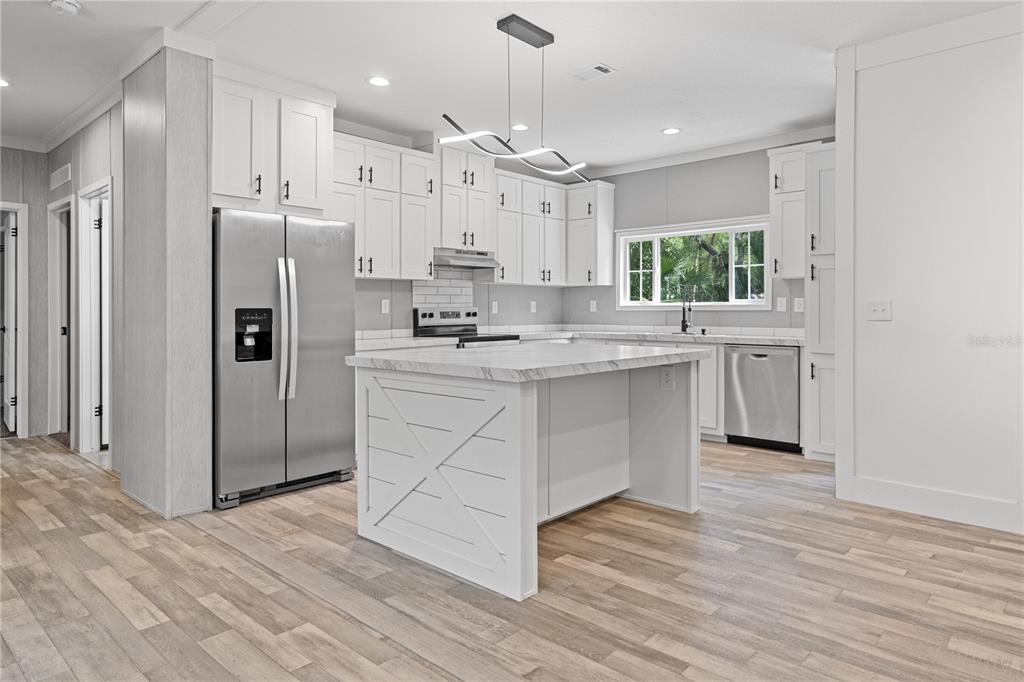 375 Sapp Street Inglis, FL 34449 - Photo 9 of 36 a kitchen with stainless steel appliances granite countertop a refrigerator a sink dishwasher a stove and white cabinets with wooden floor