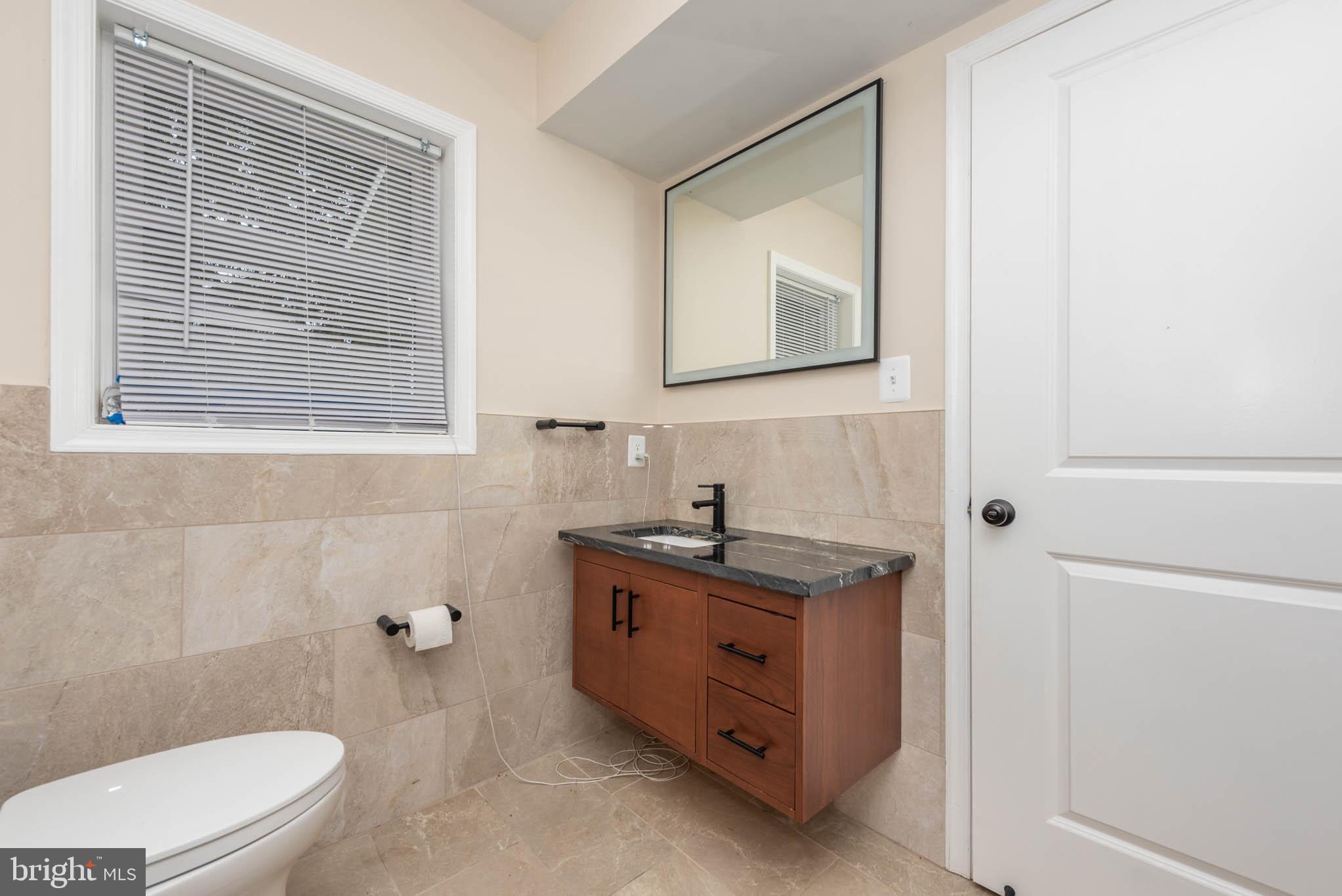 2705 Spring Hill Road Pikesville, MD 21208 - Photo 12 of 43 a bathroom with a granite countertop toilet a sink and mirror