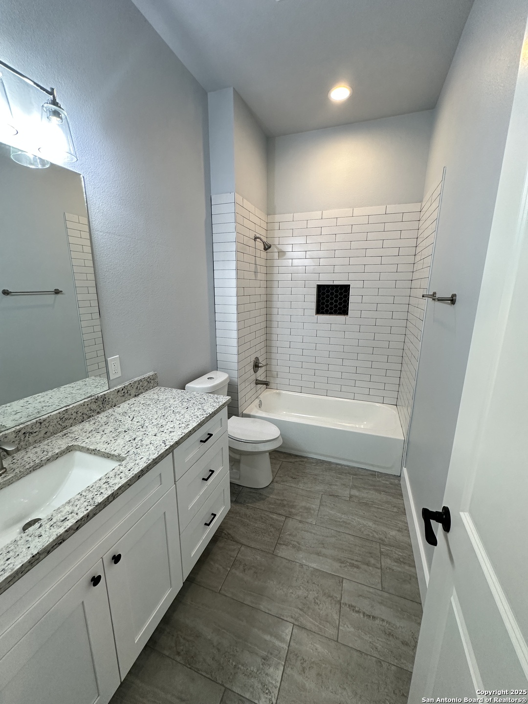 327 Ebner Street, Unit B Boerne, TX 78006 - Photo 14 of 21 a bathroom with a granite countertop sink a toilet a mirror and shower