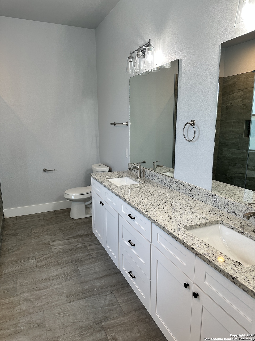 327 Ebner Street, Unit B Boerne, TX 78006 - Photo 15 of 21 a bathroom with a granite countertop sink a toilet and a mirror