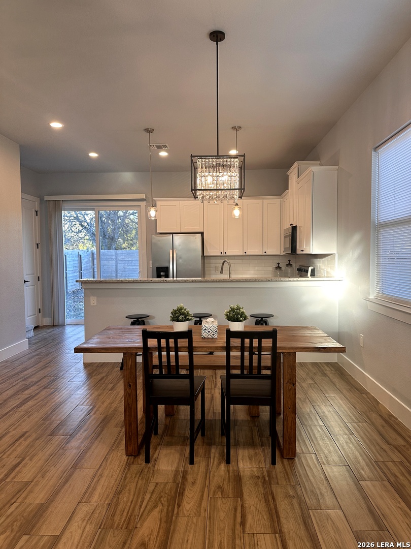 327 Ebner Street, Unit B Boerne, TX 78006 - Photo 5 of 21 a kitchen with stainless steel appliances granite countertop wooden floor window island and chairs