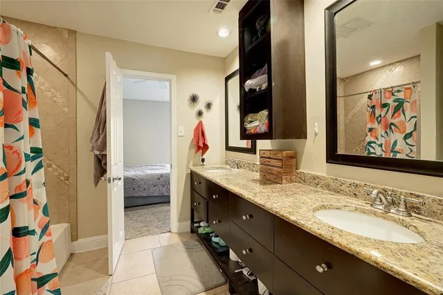 a en suite bathroom with a granite countertop double vanity sink mirror and bathtub