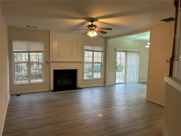 a view of an empty room with wooden floor fireplace and a window