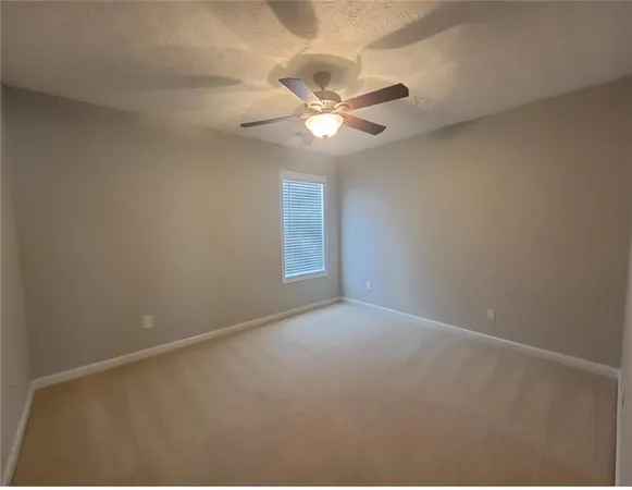 an empty room with a window and a ceiling fan