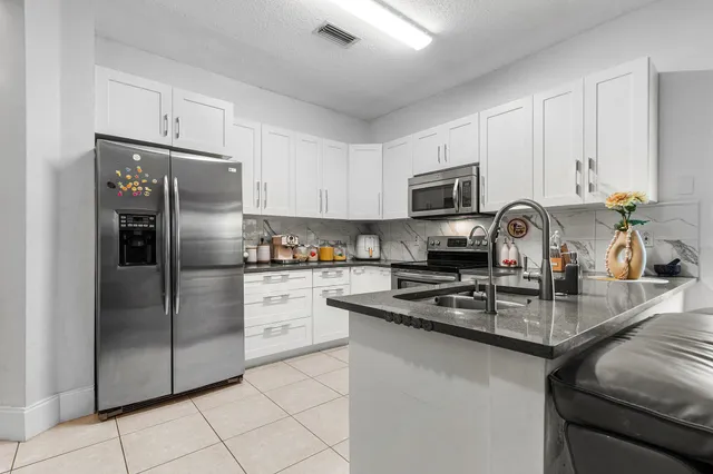 a kitchen with granite countertop a refrigerator stove and microwave
