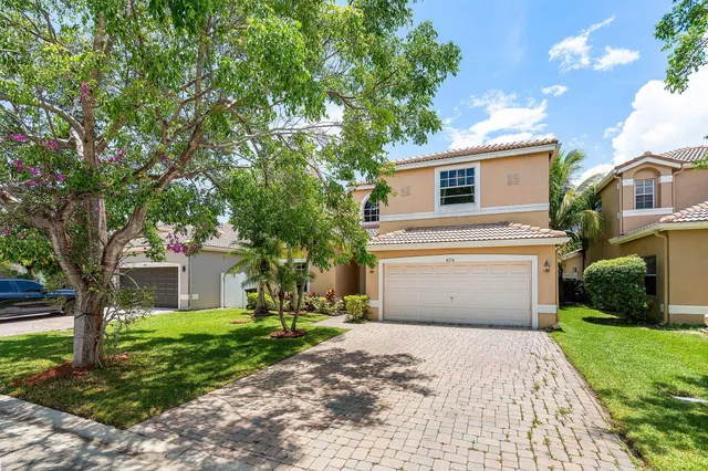 a front view of a house with a yard and an trees