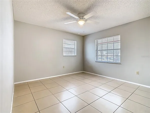 an empty room with windows and fan