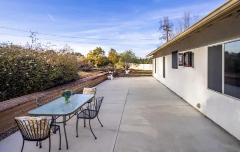 a view of a patio with table and chairs with wooden floor and fence