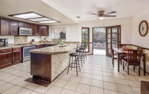 a open kitchen with stainless steel appliances granite countertop a stove top oven a sink a dining table and chairs with the cabinets