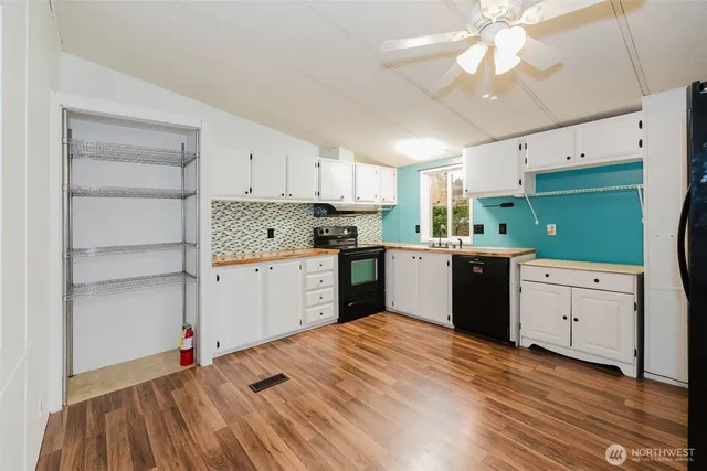 a kitchen with stainless steel appliances granite countertop a refrigerator a sink dishwasher a stove and white countertops with wooden floor