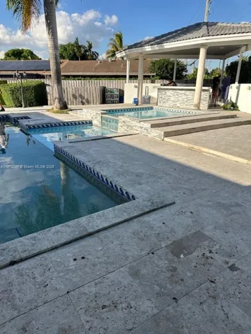 a view of a swimming pool with a lawn chairs under an umbrella