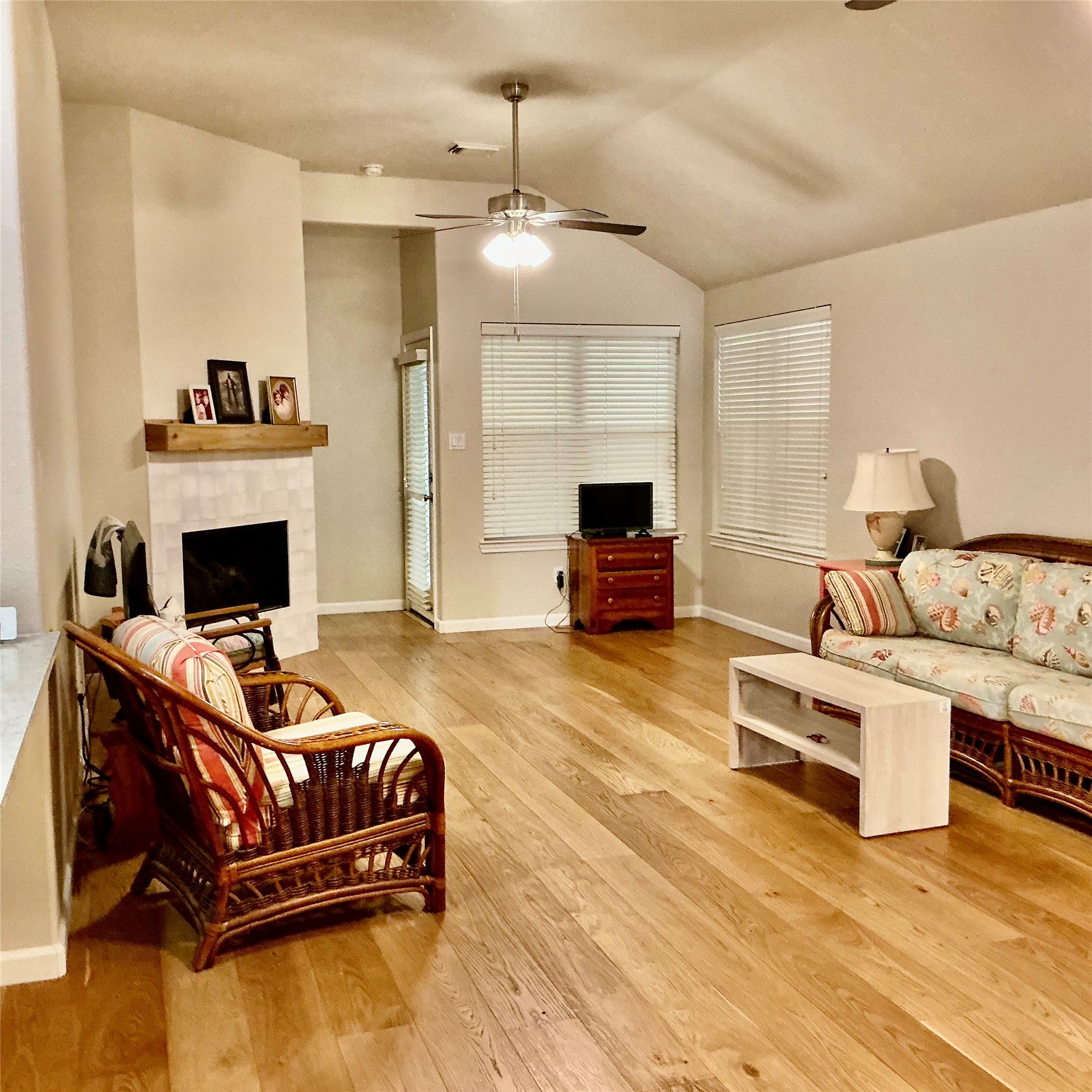 2910 Crescent Bend Road Spring, TX 77388 - Photo 9 of 29 Spacious living room with hardwood floors, a cozy fireplace, and a ceiling fan. Large windows provide natural light. Includes comfortable seating and a small media stand.