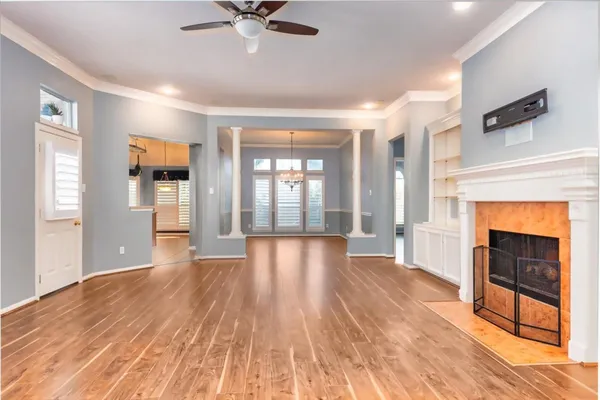 a view of an empty room with wooden floor and a window