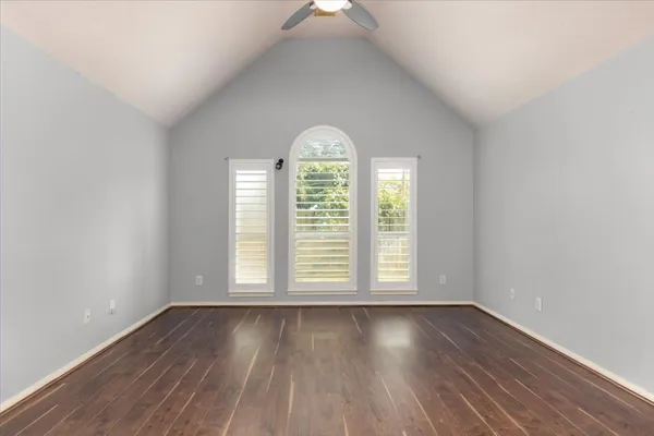 an empty room with wooden floors and windows