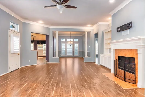 a view of an empty room with wooden floor and a window