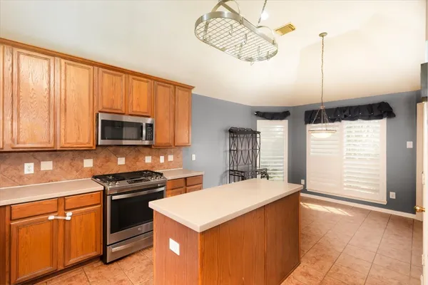 a kitchen with stainless steel appliances granite countertop a stove a sink and a microwave