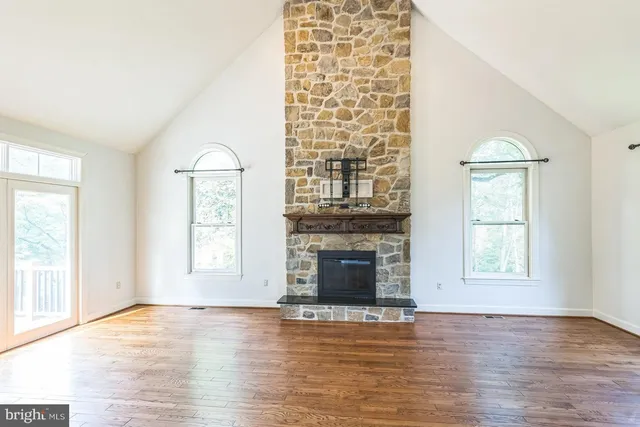an empty room with wooden floor fireplace and windows