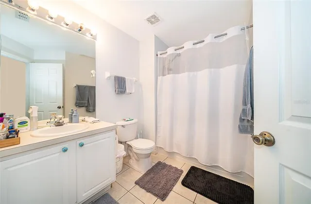 a bathroom with a sink a toilet a shower curtain and a large mirror