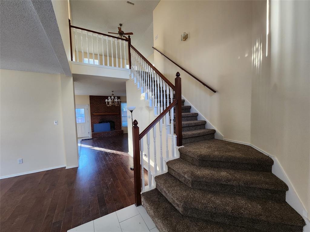 2413 Timber Ridge Lane Flower Mound, TX 75028 - Photo 4 of 32 Split-level interior featuring a carpeted staircase with white balusters and a dark wood-finish handrail