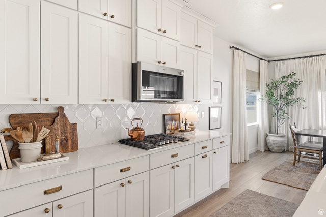 870 North Ada Loop Lehi, UT 84048 - Photo 13 of 51 White shaker-style cabinetry with brass hardware, a gas cooktop, and an over-the-range microwave