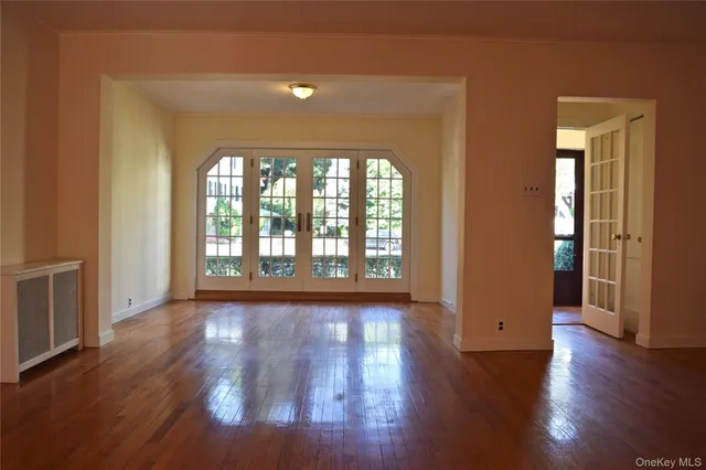 a view of an empty room with wooden floor fireplace and a window