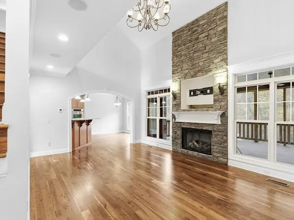 an empty room with wooden floor chandelier fan and windows