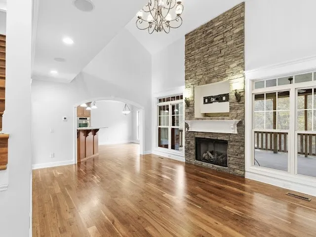 an empty room with wooden floor chandelier fan and windows