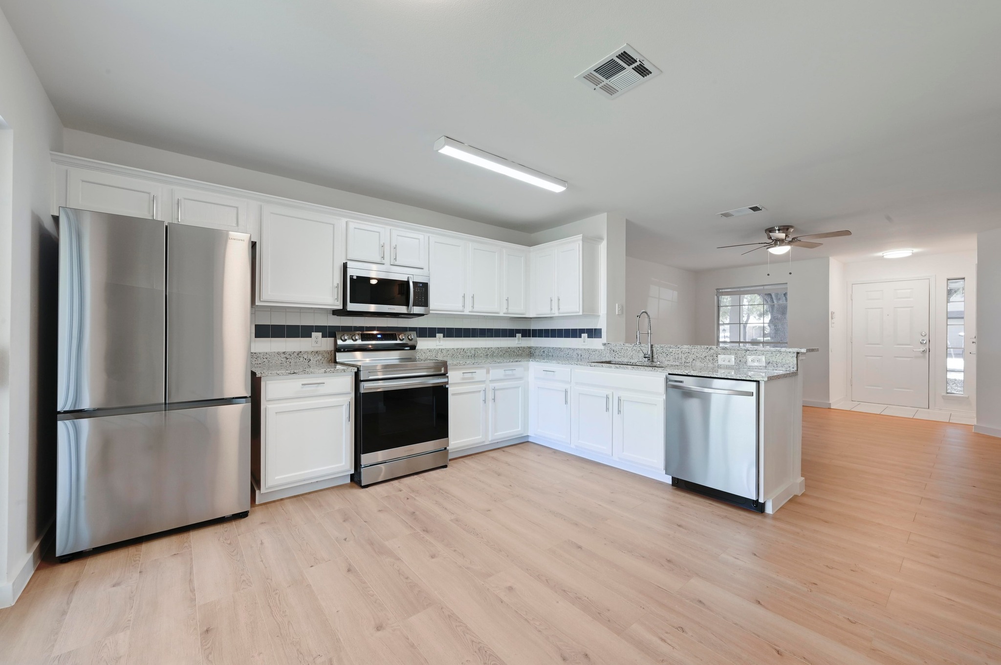 11106 Franklins Tale Loop Austin, TX 78748 - Photo 12 of 25 Kitchen with stainless steel appliances, white cabinetry, and light stone counters
