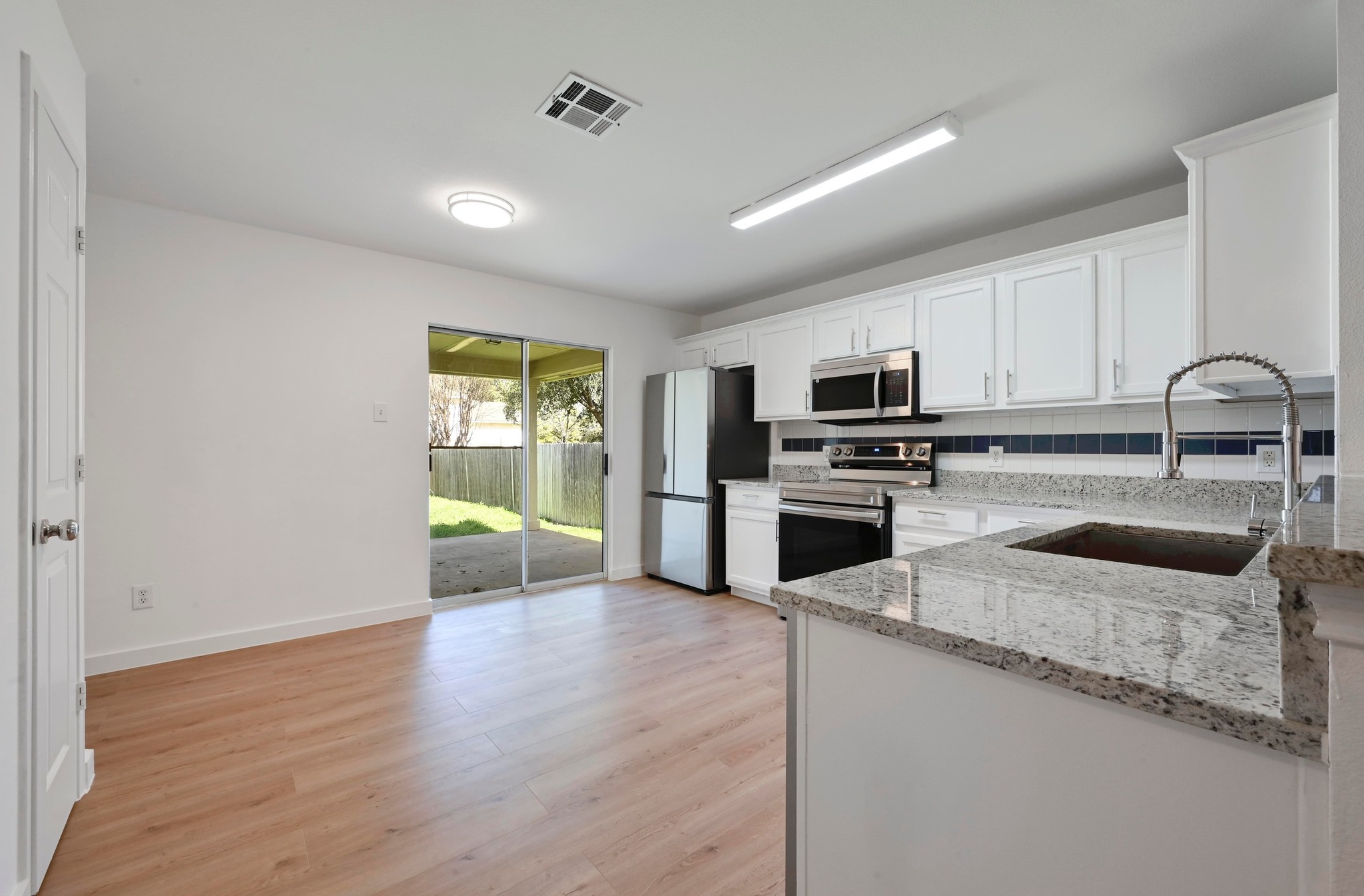 11106 Franklins Tale Loop Austin, TX 78748 - Photo 10 of 25 Kitchen featuring light stone countertops, stainless steel appliances, white cabinets, and light wood-type flooring