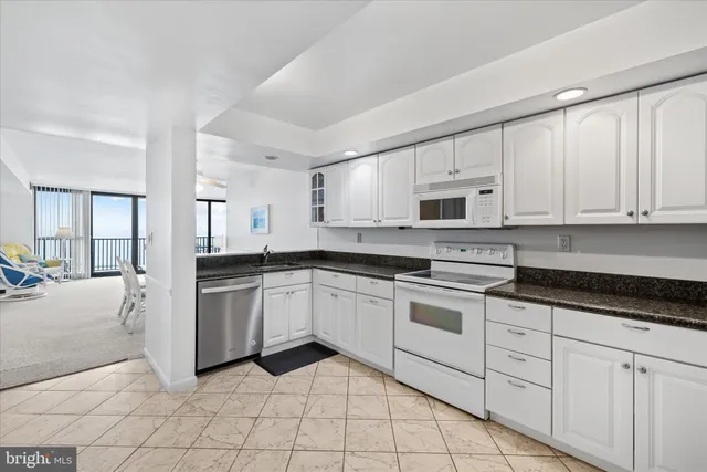 a kitchen with granite countertop white cabinets and white appliances