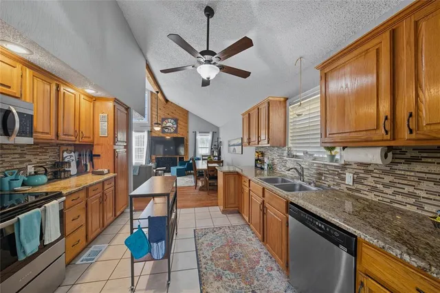 a large kitchen with stainless steel appliances granite countertop a stove a sink dishwasher a dining table and chairs with wooden floor