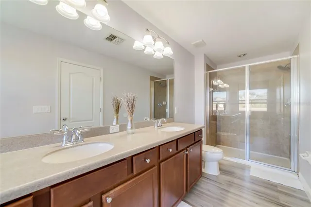 a bathroom with a granite countertop sink a toilet a mirror and shower