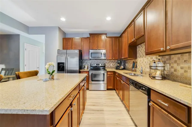 a kitchen with stainless steel appliances granite countertop a sink a stove and a refrigerator