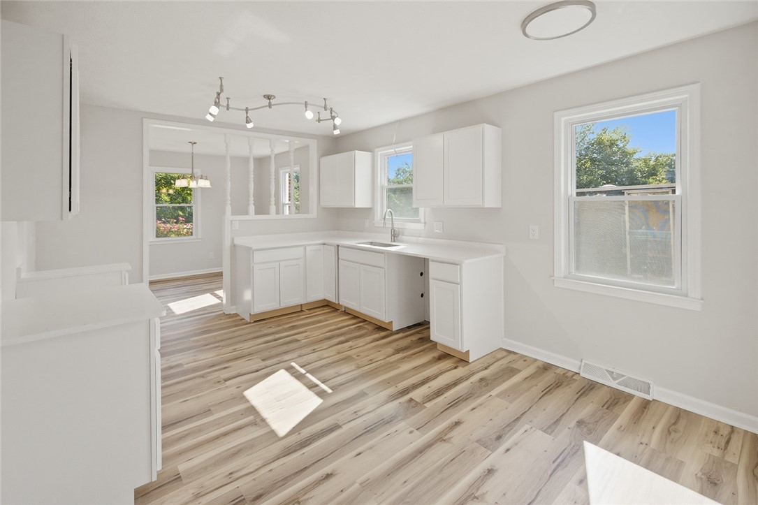902 Cherokee Road Pelzer, SC 29669 - Photo 25 of 38 A well-lit kitchen featuring resilient flooring and ample white cabinetry for storage and preparation.