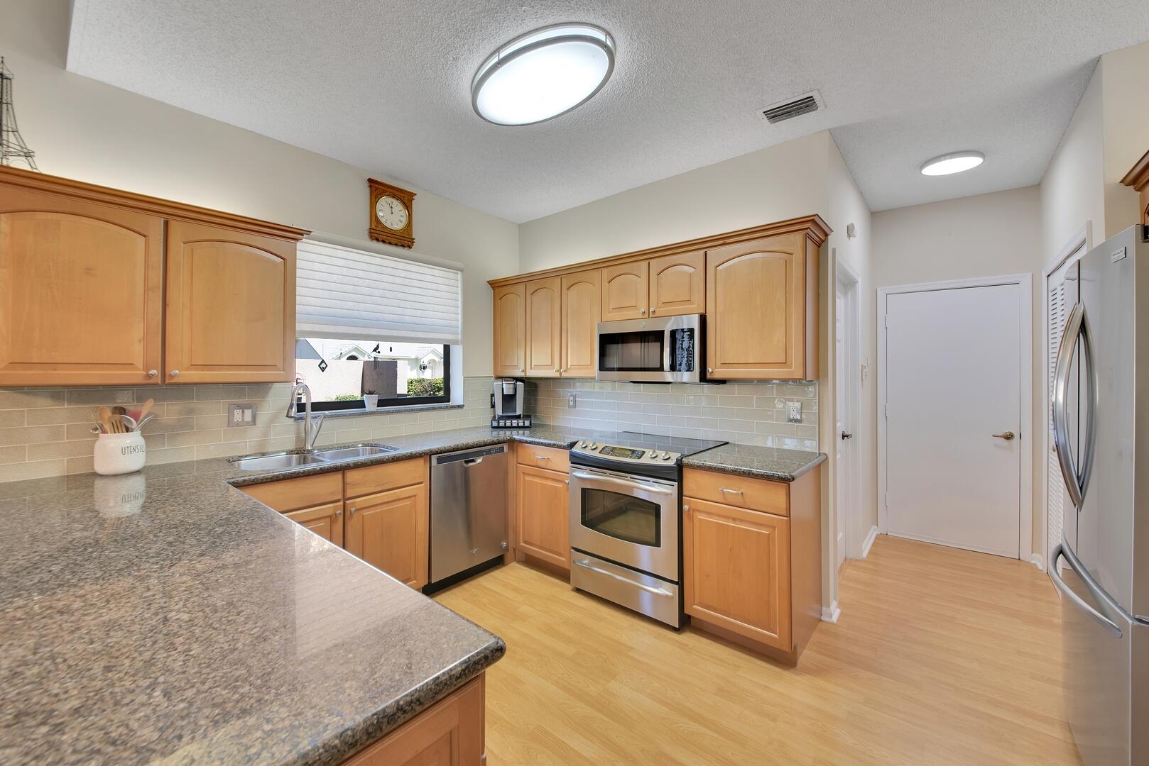 19261 Cherry Hills Terrace Boca Raton, FL 33498 - Photo 11 of 53 a kitchen with stainless steel appliances granite countertop a stove top oven a sink dishwasher a refrigerator and white cabinets with wooden floor