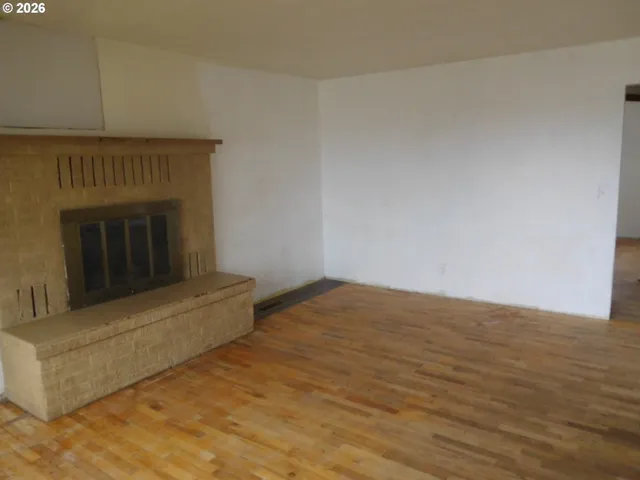 a view of empty room with wooden floor and fireplace
