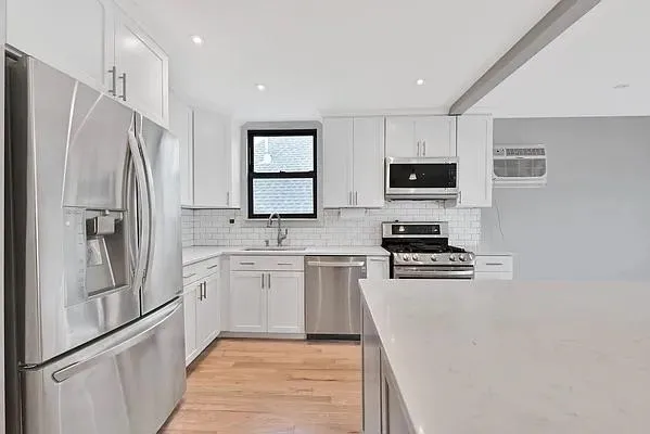 a kitchen with white cabinets and stainless steel appliances