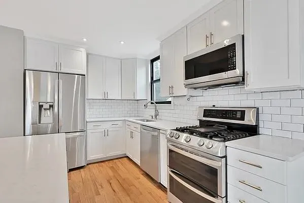 a kitchen with stainless steel appliances white cabinets a stove a microwave and a refrigerator