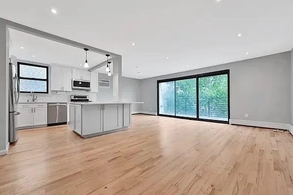 a view of kitchen with stainless steel appliances kitchen island wooden floor and window