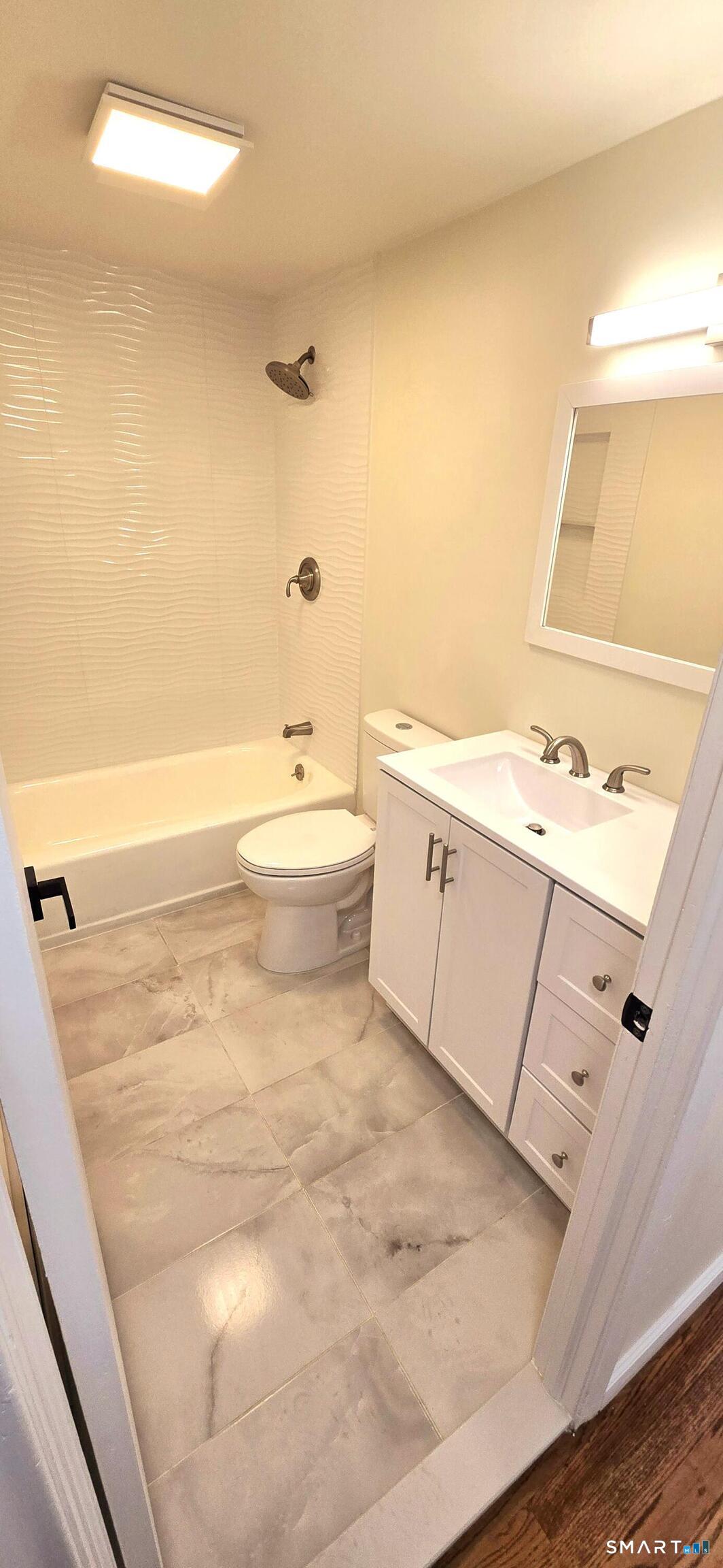 64 4th Street Bristol, CT 06010 - Photo 12 of 44 a bathroom with a white tub shower vanity and a sink