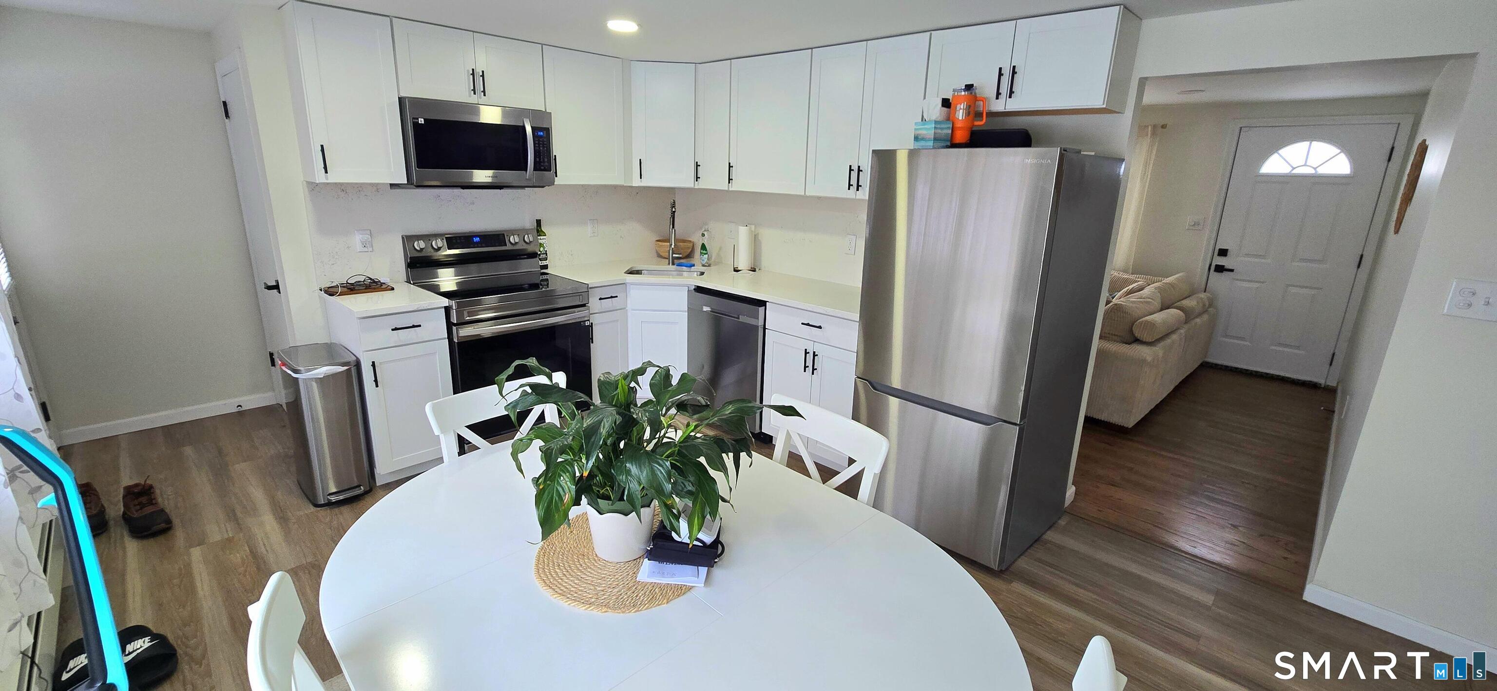 64 4th Street Bristol, CT 06010 - Photo 4 of 44 a kitchen with stainless steel appliances a dining table a microwave a refrigerator and a dining table